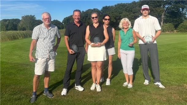 Die siegreichen Golfer haben sich in einer Reihe aufgestellt. 