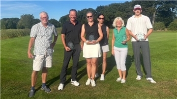 Die siegreichen Golfer haben sich in einer Reihe aufgestellt. 