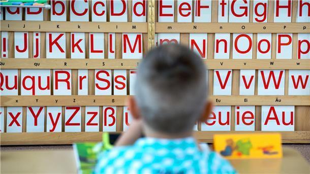 Ein Kind sitzt vor einer Tafel mit Buchstaben. Die Personalgewinnung an den Schulen war ein wichtiges Thema am Runden Tisch Bildung. 