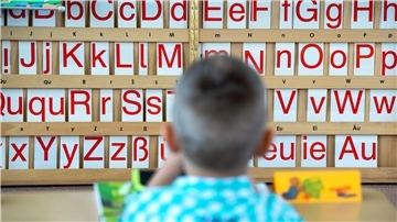 Ein Kind sitzt vor einer Tafel mit Buchstaben. Die Personalgewinnung an den Schulen war ein wichtiges Thema am Runden Tisch Bildung. 