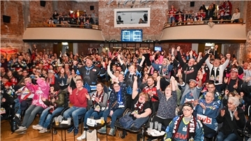 Eishockey-Fans schauen gemeinsam ein Spiel auf einer Leinwand und fiebern mit. 