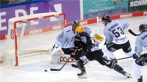 Ein Eishockeyspieler läuft aufs Tor zu und will den Puck ins Netz schießen. Die  