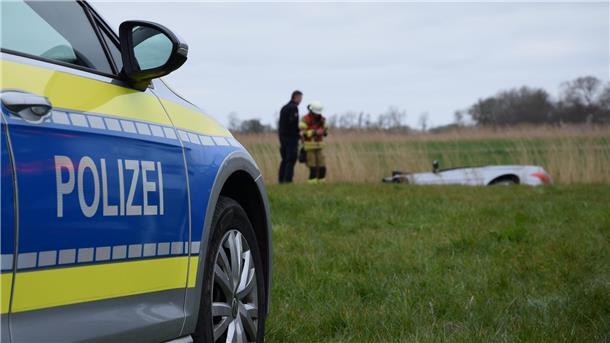 Im Vordergrund ist ein Polizeiauto zu sehen, im Hintergrund ein Polizist und ein Feuerwehrmann neben einem im Graben liegenden Auto. In der Butjadinger Wisch kam es nach einem Einbruch zu einer Verbrecherjagd.
