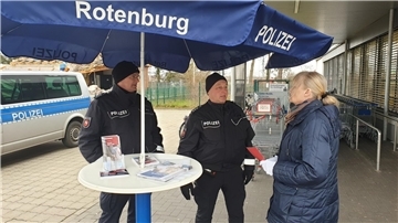 Die Polizeibeamten Rolf Meyer (Mitte) und Fred Krüger beraten die Kunden vor einem Discounter und beantworten Fragen zum Thema Taschendiebstahl.