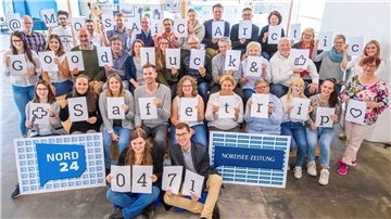 Eine große Gruppe von Menschen hält Buchstaben hoch. Sie ergeben den Text: "@MOSAiCArctic Good luck & Safe trip".