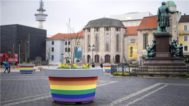 Grün, gelb oder rot? Wir haben die grauen Monsterkübel mal testweise umgefärbt Ein Kübel in regenbogenfarben ist auf einem öffentlichen Platz zu sehen.