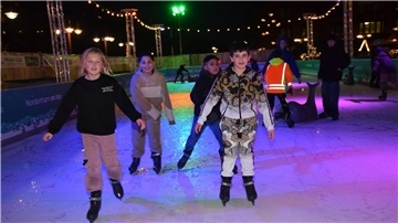 Einige Kinder und Jugendliche laufen Schlittschuh auf einer öffentlichen Eisfläche.