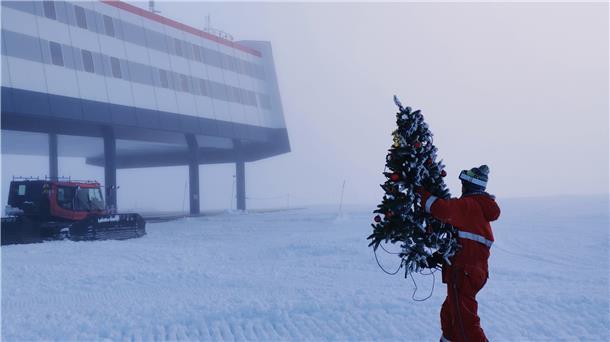 Ein Weihnachtsbaum aus Plastik wird von einem Überwinterer zur Neumayer-Station gebracht.