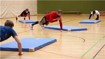 Das Foto zeigt Sportler in einer Turnhalle. 