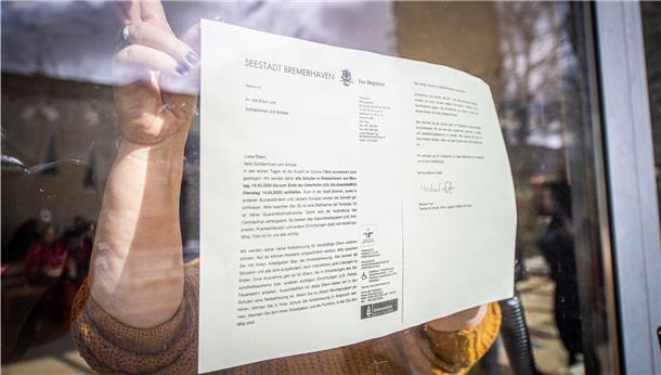 Die Schulen bleiben zu: Eine Mitarbeiterin der Goetheschule in der Deichstraße in Bremerhaven bringt die entsprechende Anweisung an die Eingangstüren an.