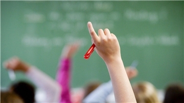 In einer Klasse hebt ein Schüler die hand. 