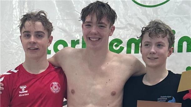 Drei Jugendliche in Schwimmkleidung mit Urkunde vor Plakatwand