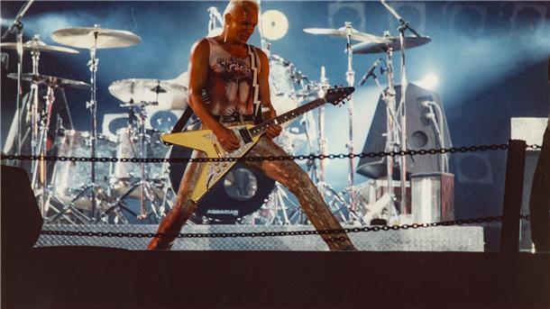 Ein Mann mit Gitarre steht auf einer Bühne.