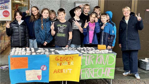 Gruppe von Kindern mit ihrer Lehrerin an einem Stand. Sechstklässler des Nordenhamer Gymnasiums sammelten in der Innenstadt für UNICEF.