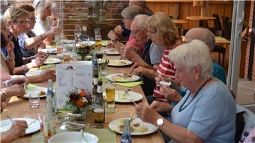 Leute sitzen an einem großen Tisch und essen Spargel. 