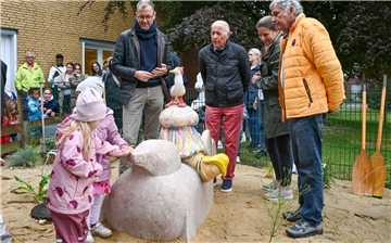 Kinder und Erwachsene stehen rund um eine Skulptur aus Ton, die Robbe, Wattwurm, Qualle und Möwe zeigt.