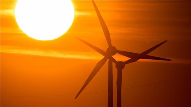 Tausende Transportanträge für Windradbau unbearbeitet Die Sonne geht hinter Windrädern auf.