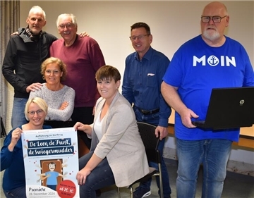 Spoaßmoaker bringen Theaterstück mit viel Aktion und Witz nach Abbehausen Drei Frauen und vier Männer bei einem Gruppenfoto. Zwei von ihnen halten ein Theaterplakat.