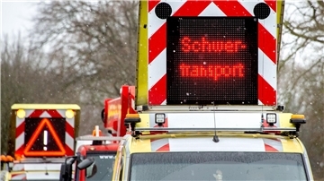 Auto mit Hinweistafel „Schwertransport“ auf dem Dach. 