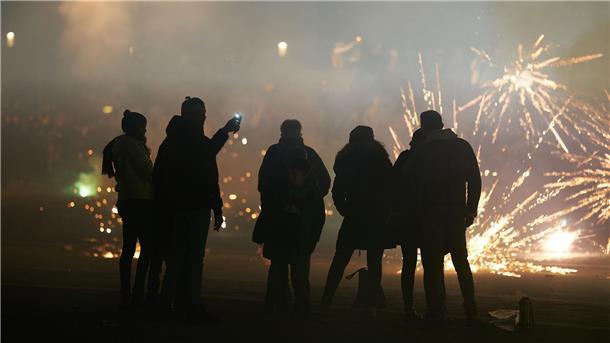 Eine Gruppe von Menschen schaut bei einem Feuerwerk zu.