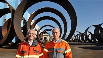 Zwei Männer vor Bauteilen für Monopiles bei Steelwind in Blexen.