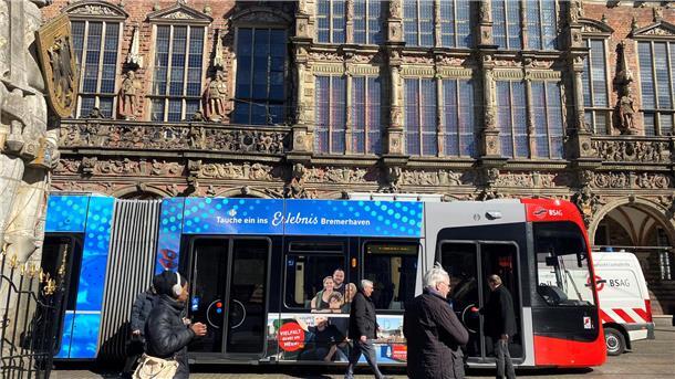 Die Straßenbahn namens „Nordlicht“ fährt mit Bremerhaven-Motiven zwei Jahre lang durch Bremen. Oberbürgermeister Melf Grantz (Mitte) steigt am Bremer Rathaus zur Probefahrt ein. 