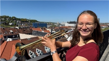 Die Trompeterin Sophie Rüth steht auf einem Kirchturm. 