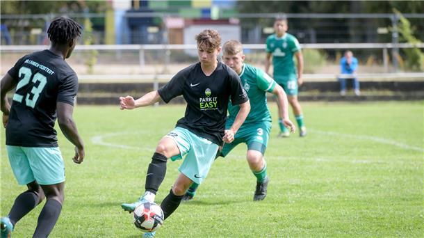 Aktives Fußballspiel. Ein Fußballer in der Mitte spielt den Ball. 