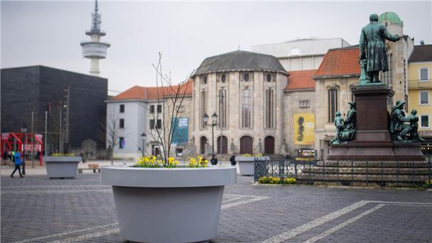 Die umstrittenen grauen XXL-Pflanzkübel „beleben“ seit Jahresbeginn 2024 den steingepflastertenTheodor-Heuss-Platz am Theater. Mit Frühlingsblüten und Bäumchen bepflanzt, sollen die „Pötte“ zur Attraktivität der Innerstadt beitragen.