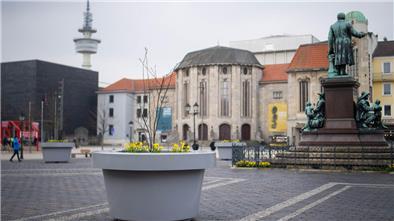 Die umstrittenen grauen XXL-Pflanzkübel „beleben“ seit Jahresbeginn 2024 den steingepflastertenTheodor-Heuss-Platz am Theater. Mit Frühlingsblüten und Bäumchen bepflanzt, sollen die „Pötte“ zur Attraktivität der Innerstadt beitragen.