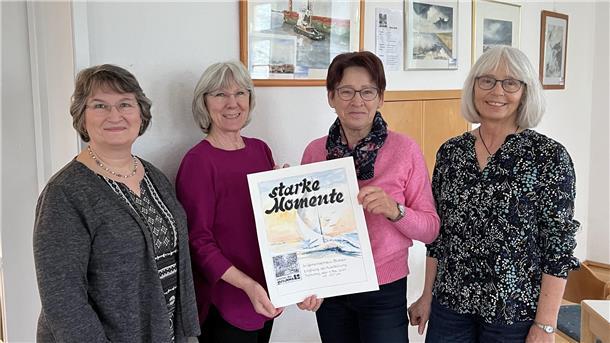 Damen halten in Blexen ein Plakat hoch zur Ausstellung - starke Momente. 