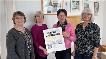 Damen halten in Blexen ein Plakat hoch zur Ausstellung - starke Momente. 