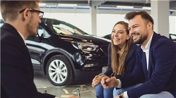 Verkaufsgespräch in einem Autohaus zwischen einem jungen Paar und einem Verkäufer