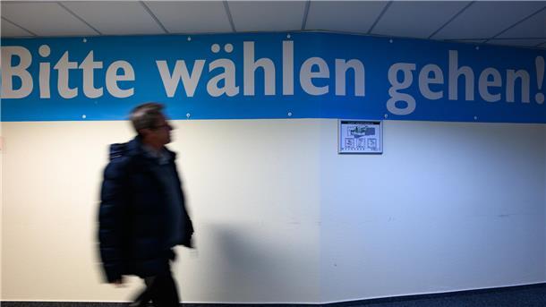 Ein Mann geht an einer Wand mit der Inschrift "Bitte wählen gehen!"