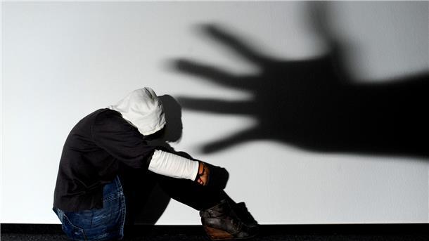 Schatten einer Hand über sitzender Frau. 