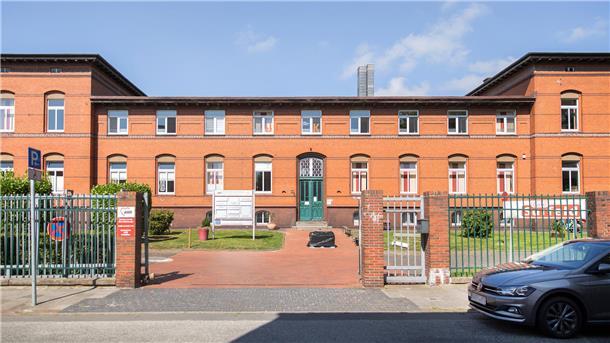 Es fehlt das Geld: Tafel Bremerhaven muss Ende des Jahres schließen Backsteingebäude mit grüner Eingangstür hinter einem Zaun, das Eingangstor zum parkartigen Gelände steht offen