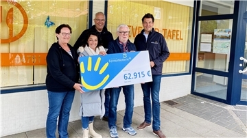 Menschen halten gemeinsam einen Scheck in der Hand.