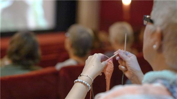 Diese Frau hat ihr Strickzeug mit ins Kino gebracht.
