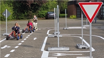 Kinder sind mit Roller und Kettcars auf einem Verkehrsübungsplatz in Brake unterwegs.