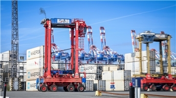 Stelzenfahrzeug vor Containern. 
