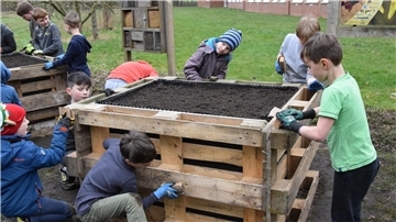 Diesen Jungs gefällt das Gärtnern in der Schule, die gemeinsam ein Hochbeet bauen und engagiert bei der Sache sind.