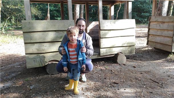 Abenteuer für Kinder auf Zevens größtem Spielplatz Ein Mann hockt hinter einem kleinen Jungen in gelben Gummistiefeln.