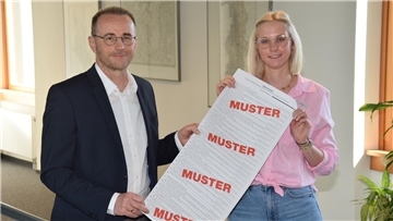 Ein Mann und eine Frau halten einen Muster-Stimmzettel für die Europawahl in die Kamera.