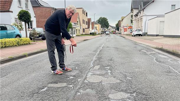 Dieter Allmers zeigt auf die Schäden, die sich aufgrund des starken Verkehrs auf der Atenser Allee gebildet haben.