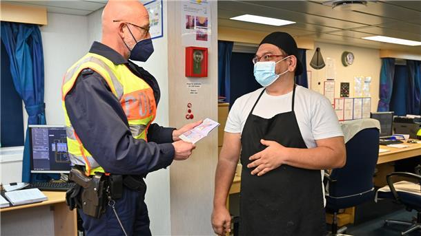 Dirk Hermann kontrolliert den Pass von Crew-Mitglied Romeo Calderon. Der geht in Bremerhaven an Bord und ist in den kommenden fünf Monaten auf See.