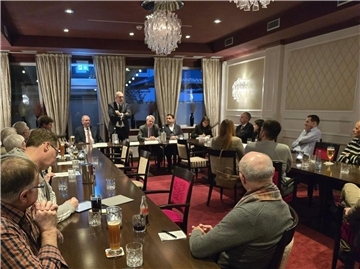 In einem Raum in einem Hotel sitzen mehrere Menschen an Tisch. Es handelt sich um einen Diskussionsabend zum Thema Energy-Port in Bremerhaven. 
