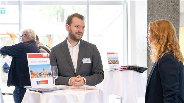 Ein Mann und eine Fraue stehen an einem Tisch und führen ein Gespräch.