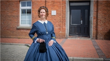 Frau in historischem Kostüm vor altem Haus