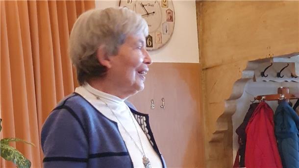 Wertschätzung im Fokus beim Weltfrauentag des SoVD Wilstedt Eine ältere Frau mit grauen Haaren und blau-weißem Outfit spricht lächelnd vor einer Gruppe.