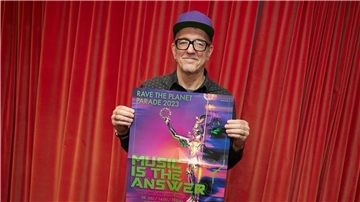 Dr. Motte hält das Plakat zur jetzt doch stattfindenden Techno-Parade hoch.